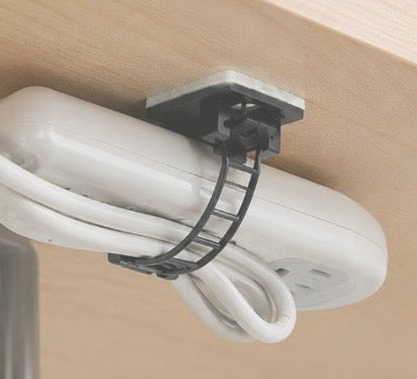 Pack of 25 Problems Solved 3M self-adhesive cable organizers for desk, shown attached to a workspace surface.