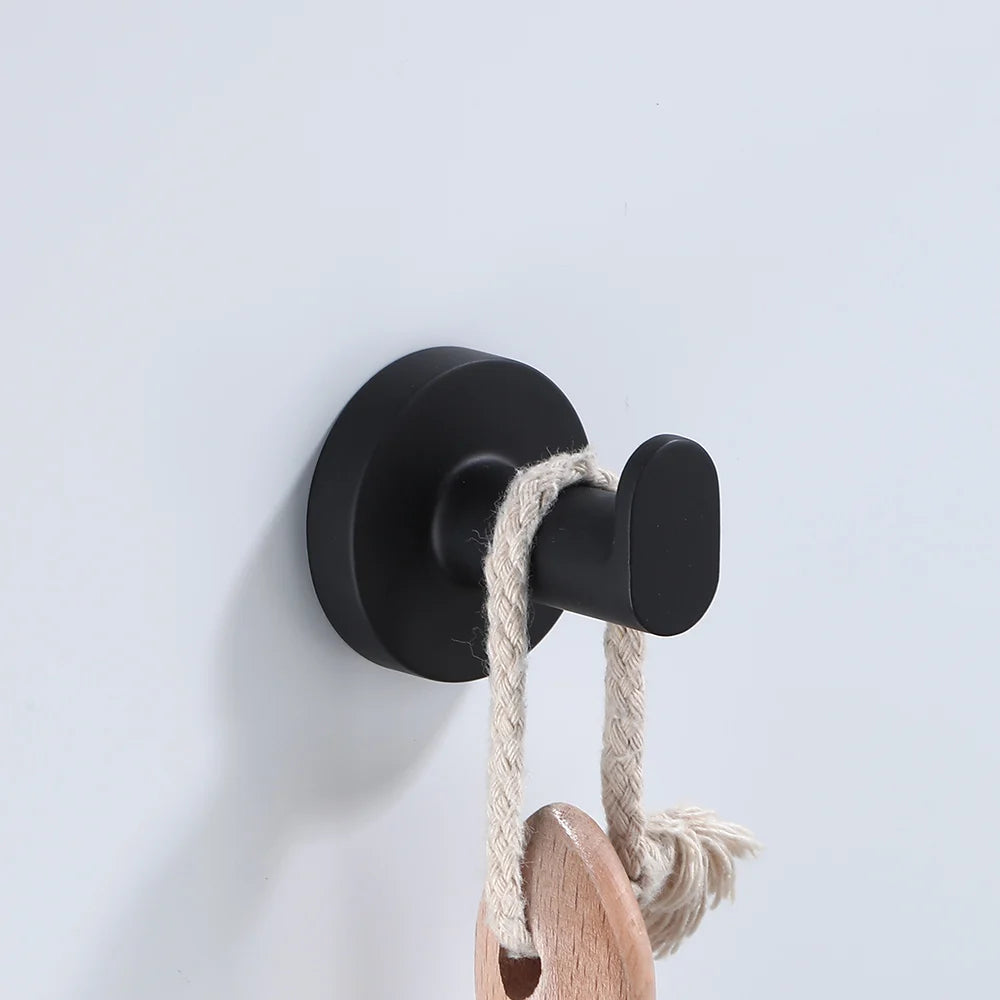 Black bathroom hardware set including robe hook, towel rail, bar rack, shelf, and tissue paper holder by Problems Solved